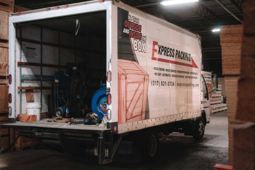 an Express Packing truck parked in a warehouse with open back doors
