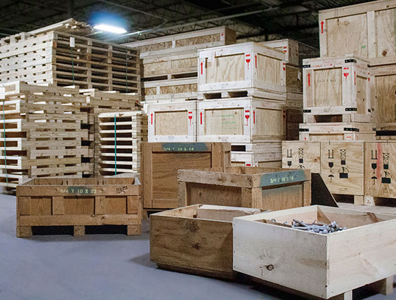 Assortment of wooden crates and pallets stacked in a warehouse 576 x 436